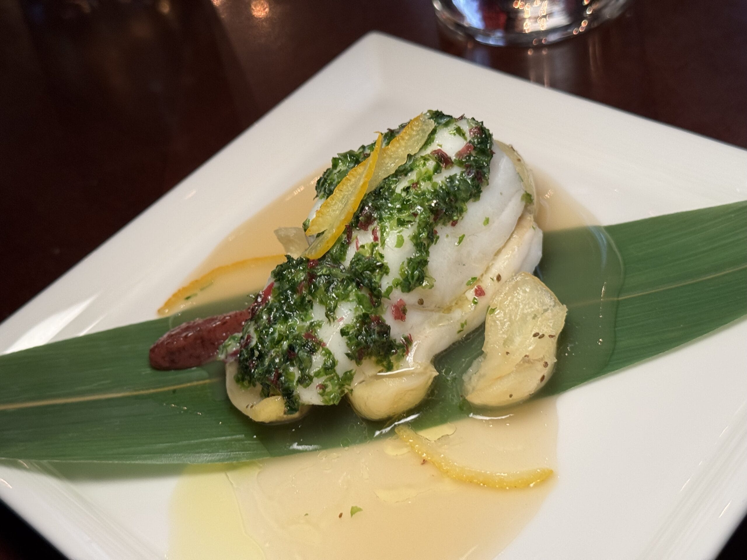 White fish fillet with herbs and citrus zest, served at the 2025 Food and Wine Festival in Tokyo DisneySea.