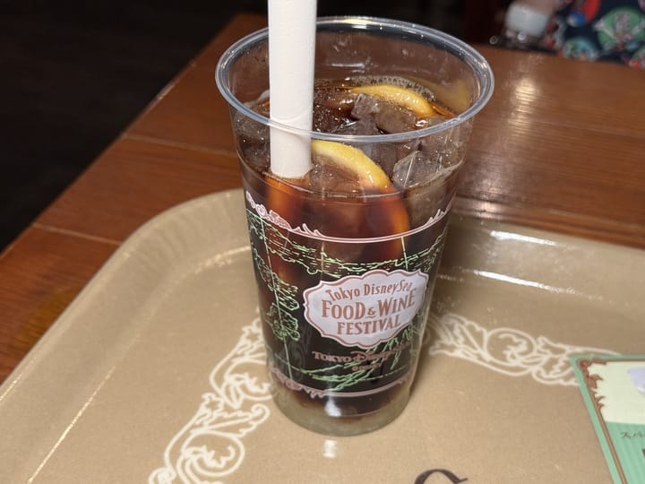 A plastic cup of iced drink with lemon slices at the 2025 Tokyo DisneySea Food and Wine Festival, on a tray.