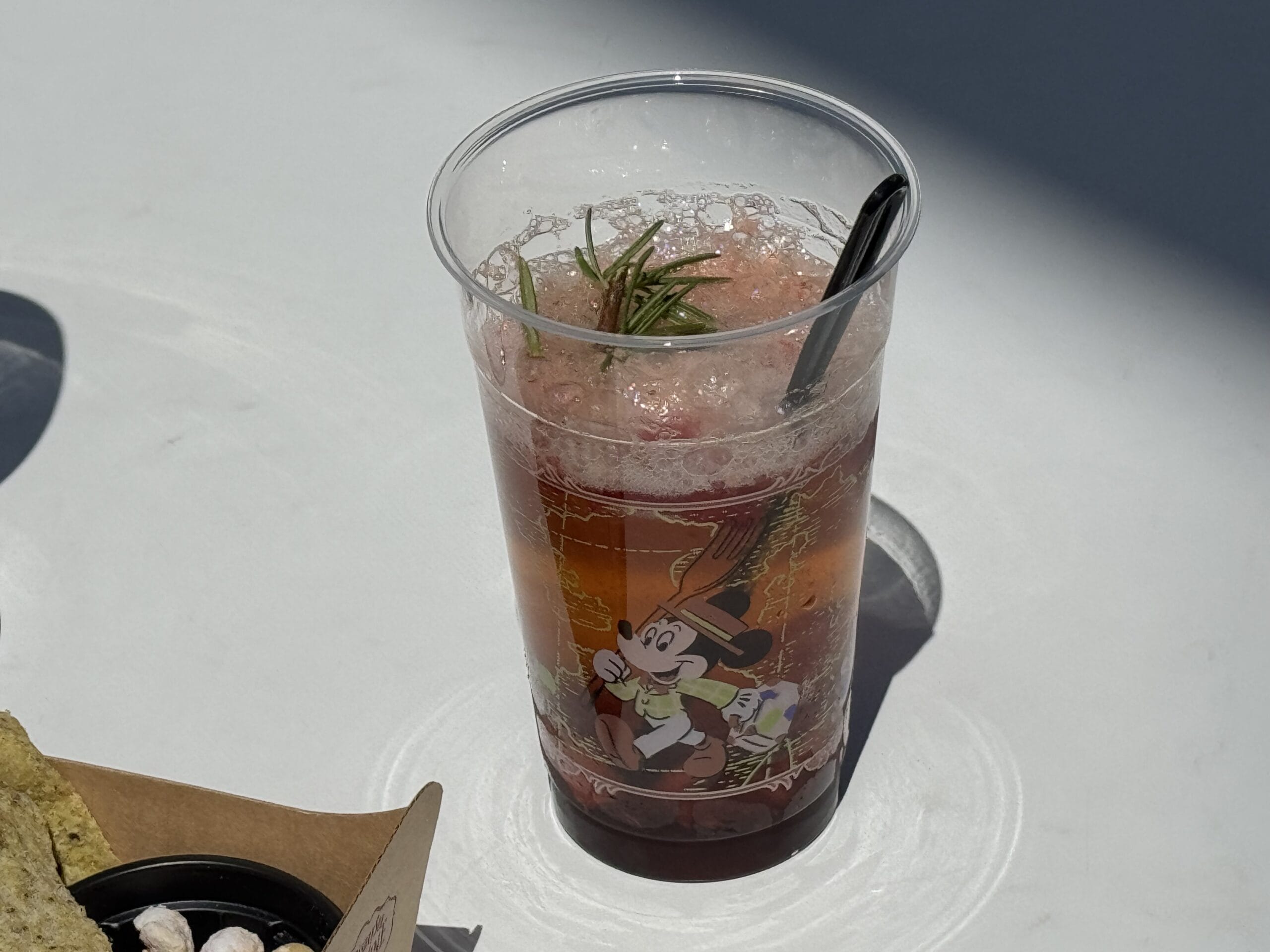 Plastic cup with red fizzy drink, ice, and cartoon character from Tokyo DisneySea's 2025 Food and Wine Festival.