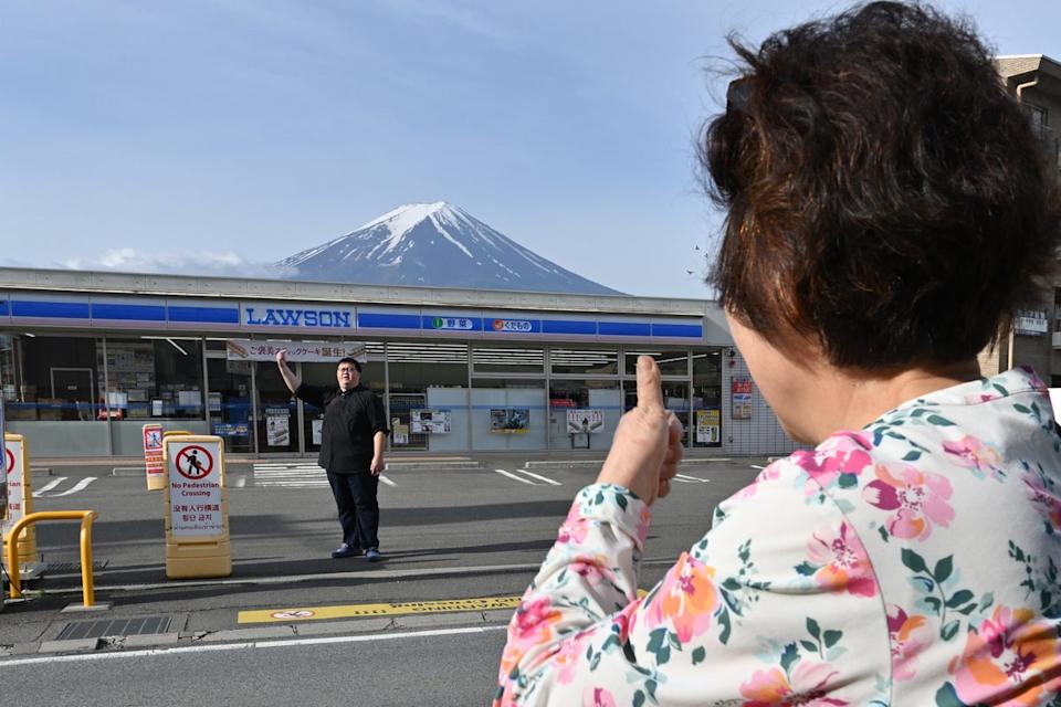 File. A person takes pictures of Mount Fuji from across the street of a convenience store in the town of Fujikawaguchiko, Yamanashi prefecture on 21 May 2024 (AFP via Getty Images)