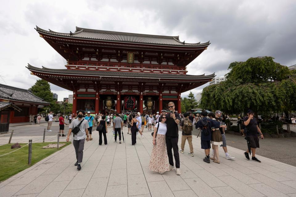 Tourists take selfies in front of Buddhist temple.