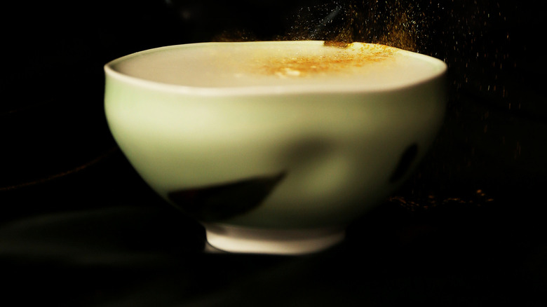 A cocktail in a ceramic pale green cup with gold dust on top