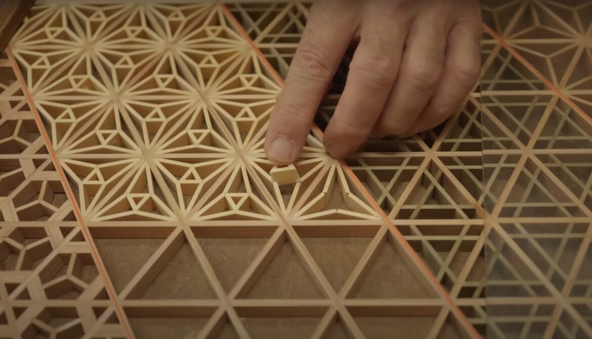 a hand slotting a piece of wood in a motif