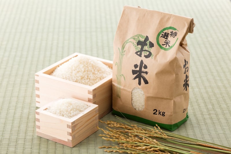 2kg bag of rice next to several wooden vessels filled with rice 