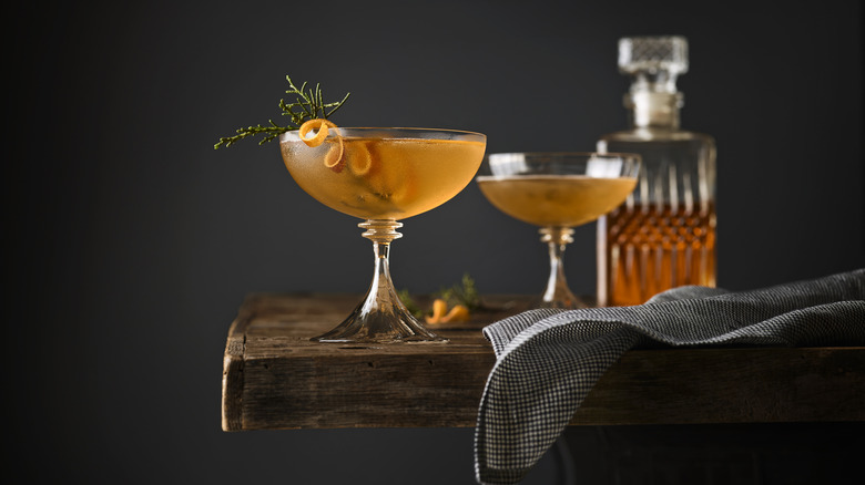 A pale orange cocktail in a coupe glass garnished with an orange twist.