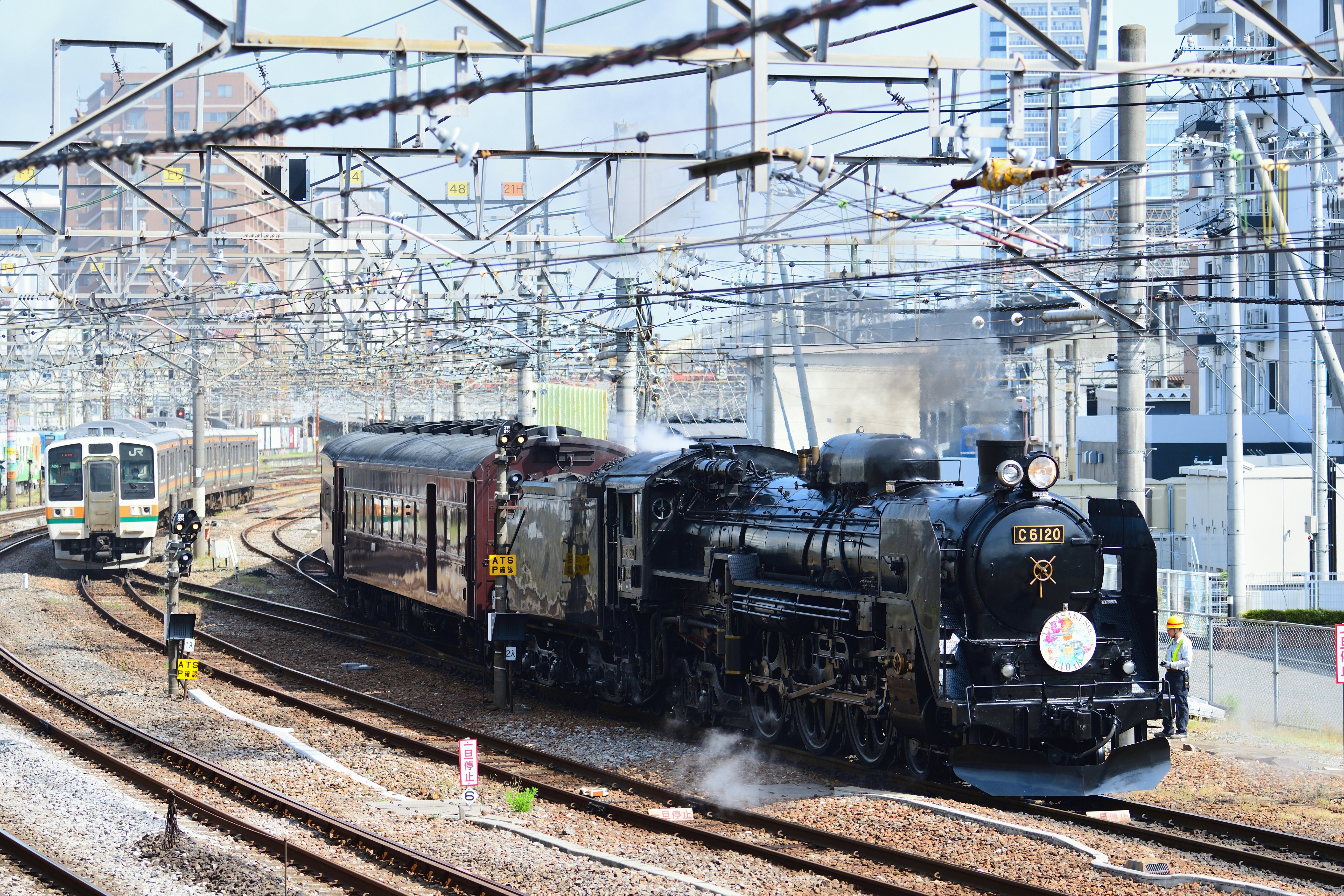 A C61 steam locomotive pulls an old Japan Railways train at the Takasaki Rolling Stock Center, Japan.