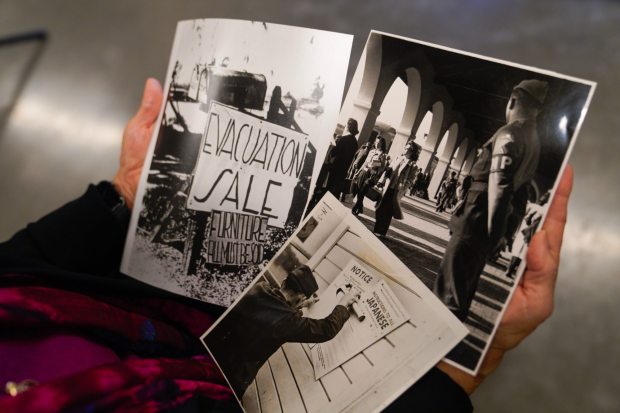 Kay Ochi, president of the Japanese American Historical Society of San Diego, holds several historical photos taken during the time when San Deigns with Japanese ancestry were taken to internment camps. (Nelvin C. Cepeda / The San Diego Union-Tribune)