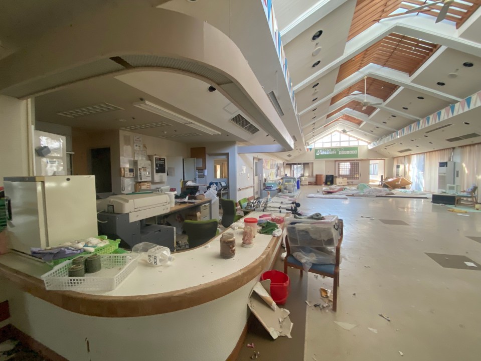 Interior of an abandoned building in Fukushima, Japan, showing debris and damaged areas.