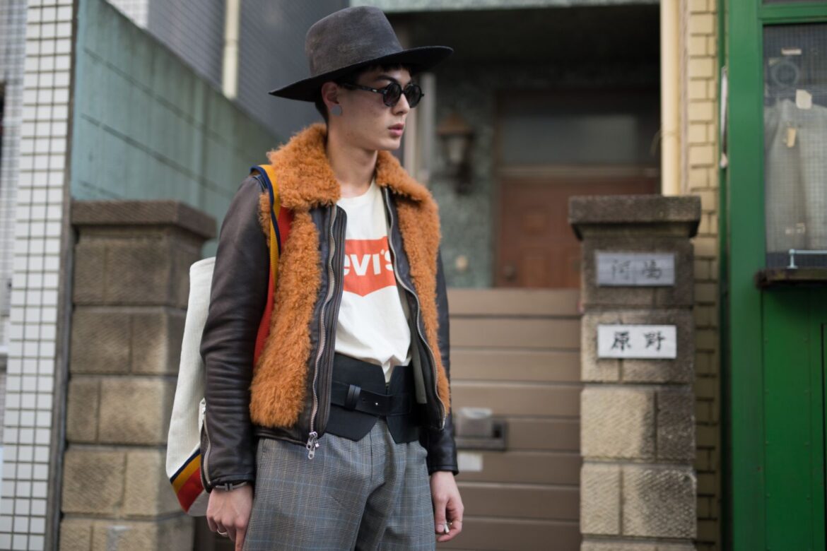 TOKYO, JAPAN - MARCH 24: A guest is seen on the street wearing a black brimmed hat, orange fur vest, black jacket, white Levi