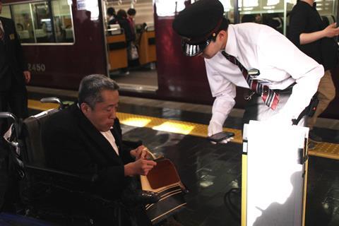 A member of Hankyu staff assisting a man who is a wheelchair user
