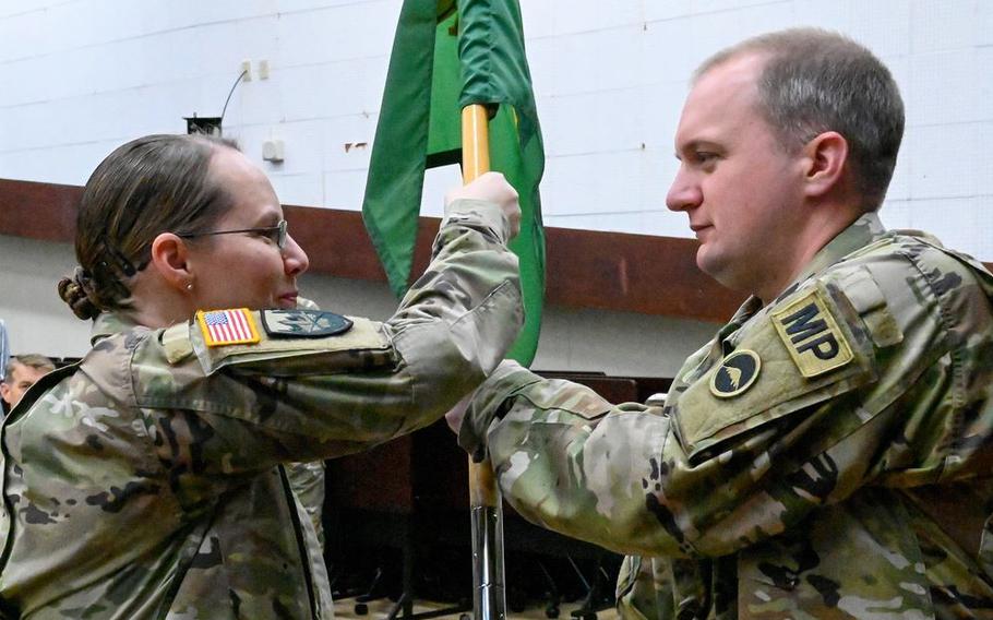 U.S. Army Garrison Okinawa Lt. Col. Rachel Bowers, commander, passes the detachment guidon to Capt. Lawrence Jerichow, incoming 247th Military Police Detachment commander, during a change of command ceremony at Torii Station, Japan, May 13, 2025. Soldiers and leaders gathered to witness the symbolic transfer of authority.