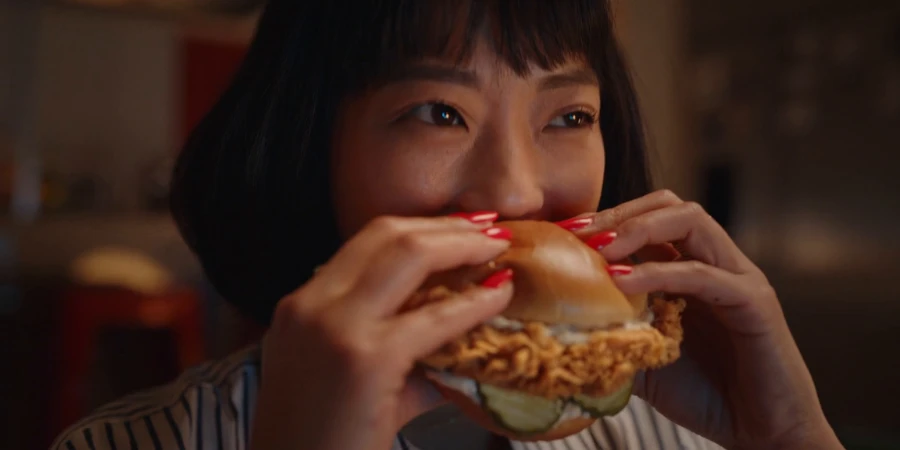 A woman enjoying her crispy fried chicken sandwich from KFC Japan
