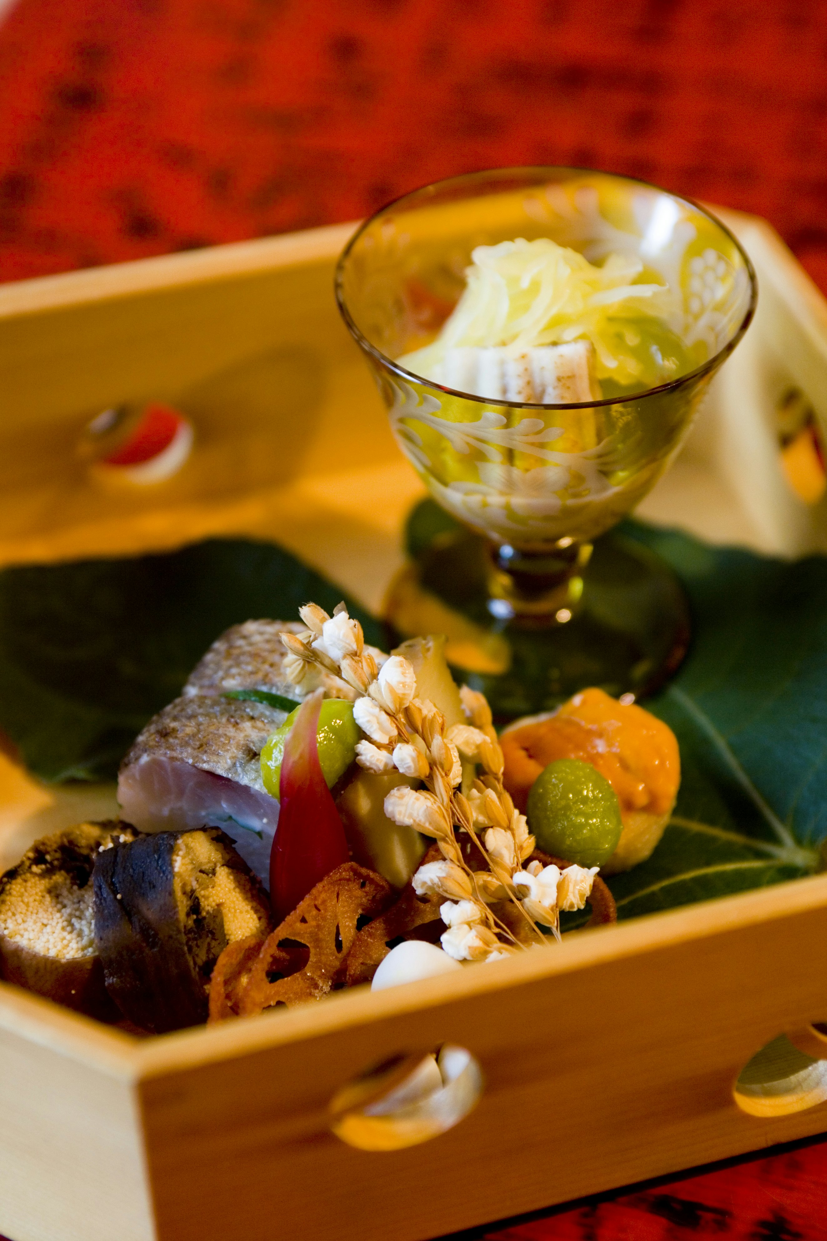 A wooden tray holding small beautifully presented dishes with autumn colors and garnish