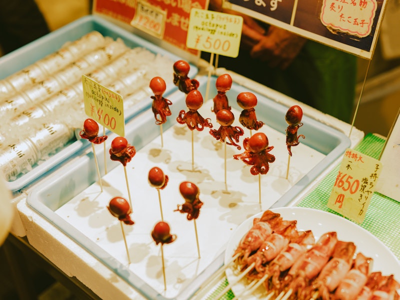 A tray of tiny octopuses on wooden sticks