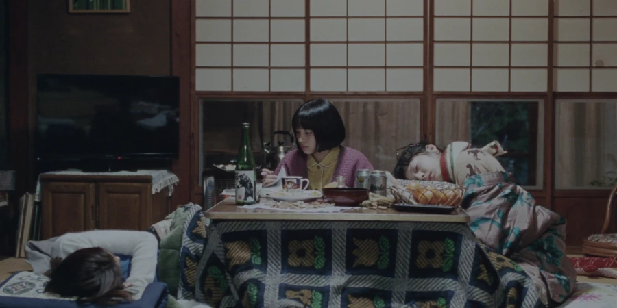 Three girls relaxing in a room with a kotatsu, food and drinks