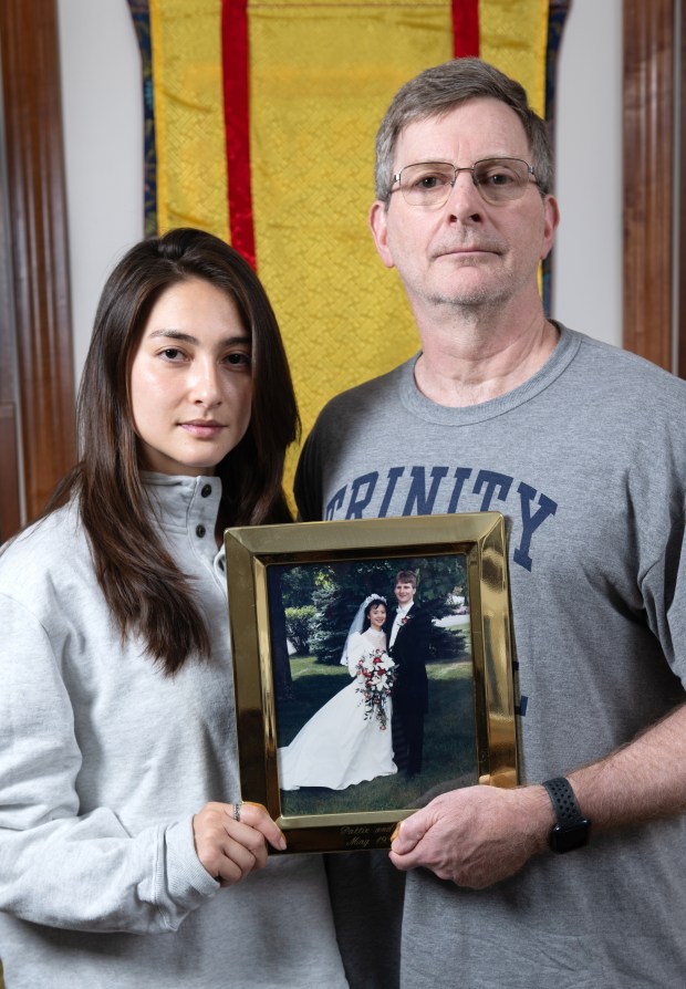 Kirk Murad and his daughter Murphy sit in the living room of their home with a photo of Kirk and his wife, Patricia Wu-Murad, on their wedding day 33 years ago, Storrs, Conn., August 25, 2023. Wu-Murad went missing in April while on a pilgrimage hiking through the mountains of Japan. A search and rescue person found evidence in late April that led the family to state that Wu-Murad is deceased. (Photo by Cloe Poisson/Special to the Court