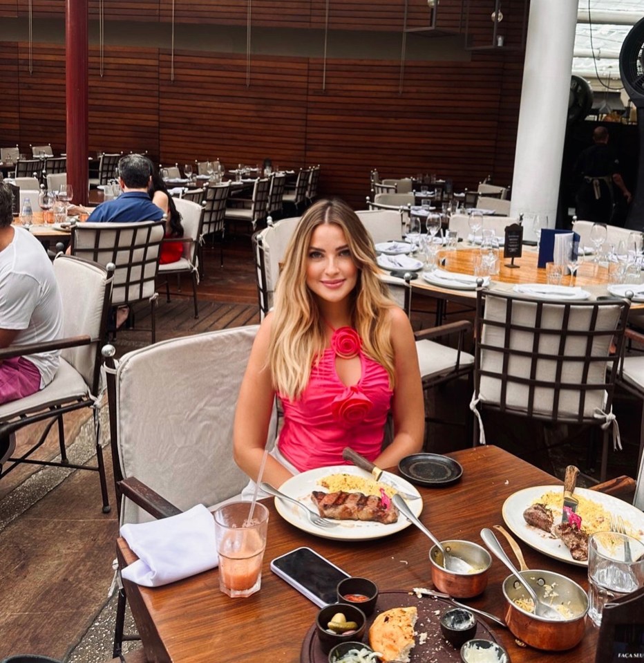 Woman sitting at an outdoor restaurant table eating a steak.