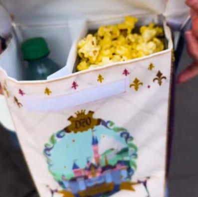 A box with popcorn and a bottled drink inside, featuring a colorful castle like the Tokyo Disneyland Popcorn Pouch.