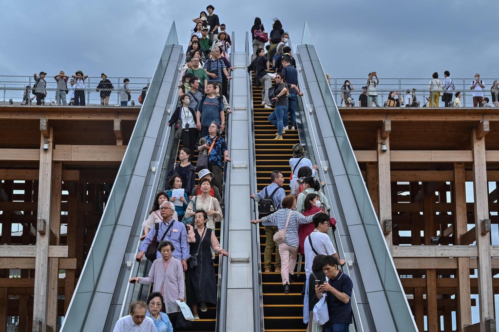 People ride one of the outdoor escalators at the 2025 Osaka Expo on May 21. Escalator etiquette in Japan requires users to stand on one side to allow others in a hurry to walk up the free side of the escalator. Photo: AFP