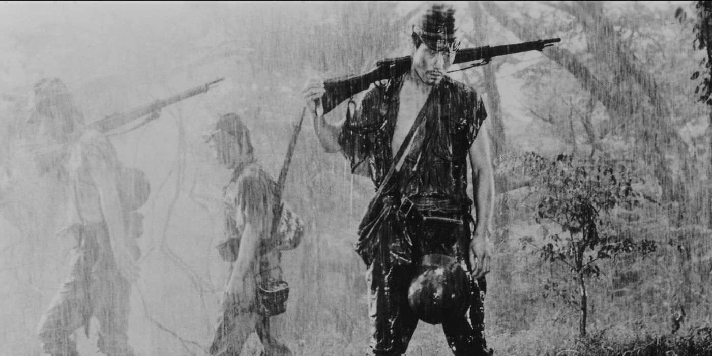 Tamura (Eiji Funakoshi) standing in the heavy rain holding a gun in Fires on the Plain