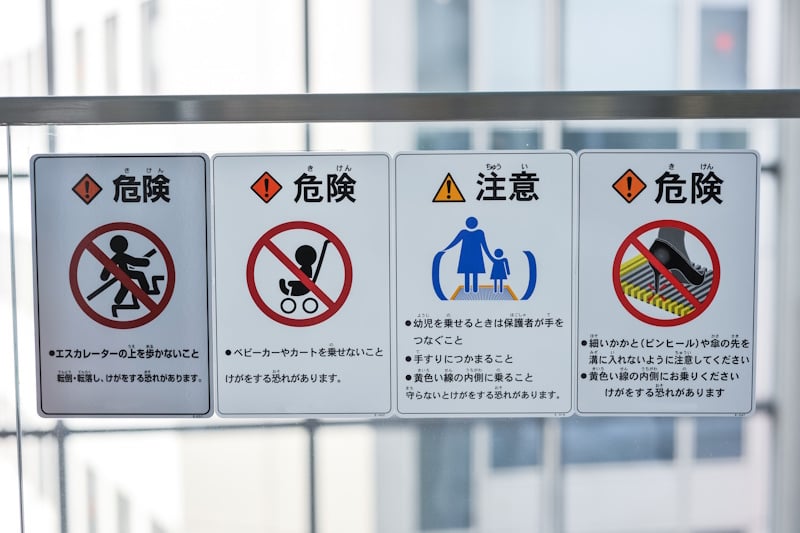 A series of escalator safety signs. The leftmost sign urges people not to walk on escalators as it can lead to falls or injuries.
