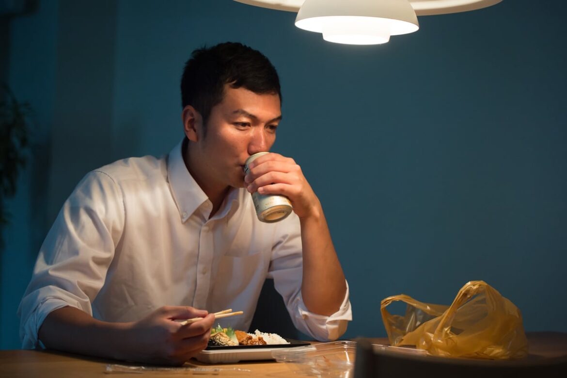 Man eating a bento box and drinking beer by himself