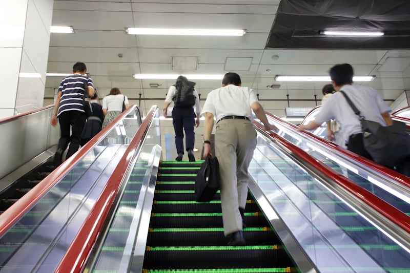 People walking up escalators in a train station