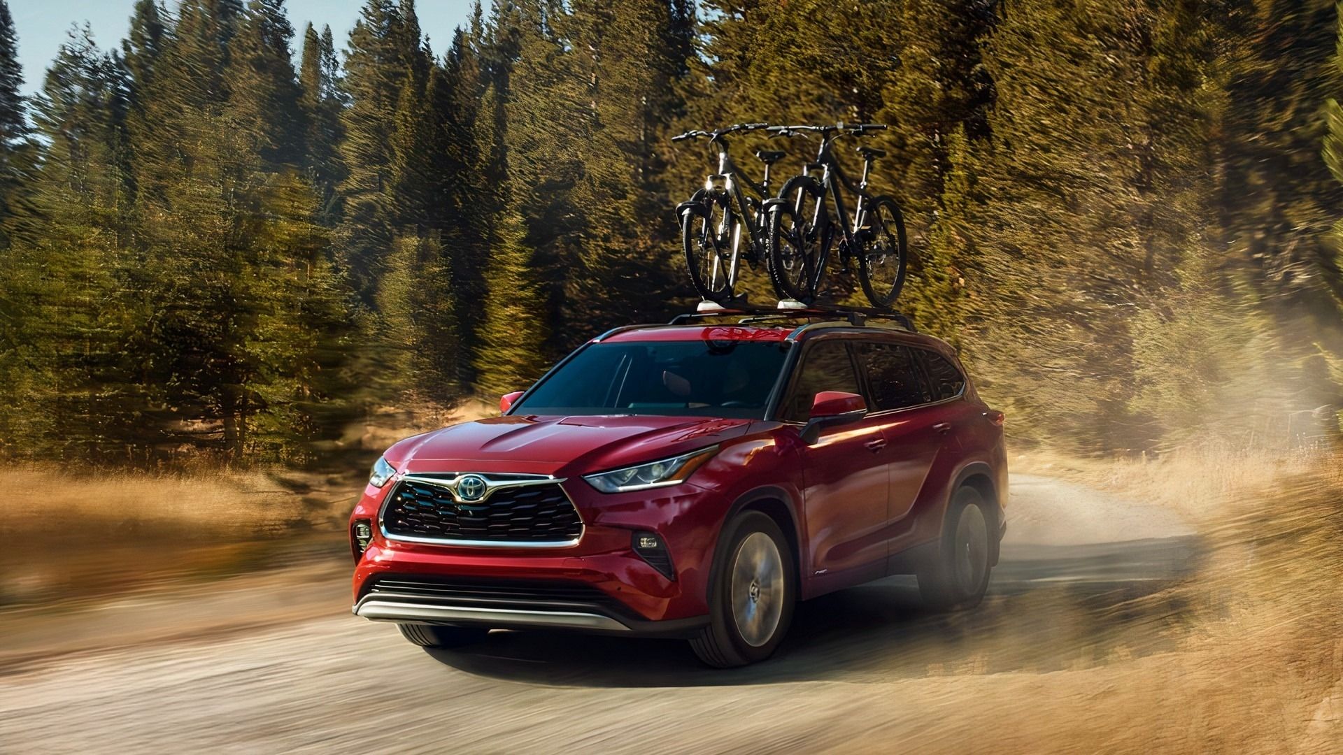 Red 2023 Toyota Highlander Hybrid SUV on a dirt road