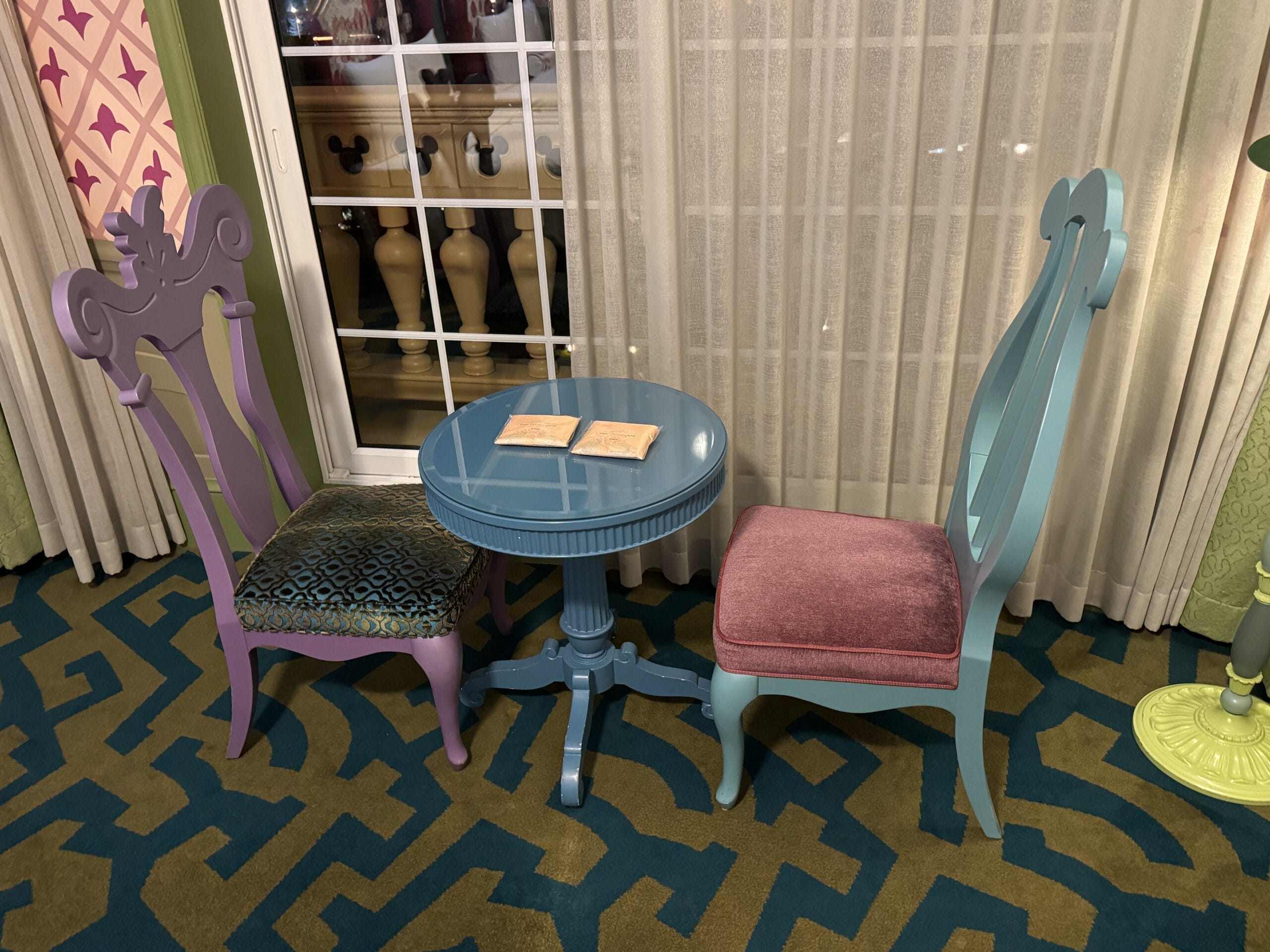 Two ornate chairs and a table with a book, evoking an Alice in Wonderland hotel room tour near Tokyo Disneyland Hotel.