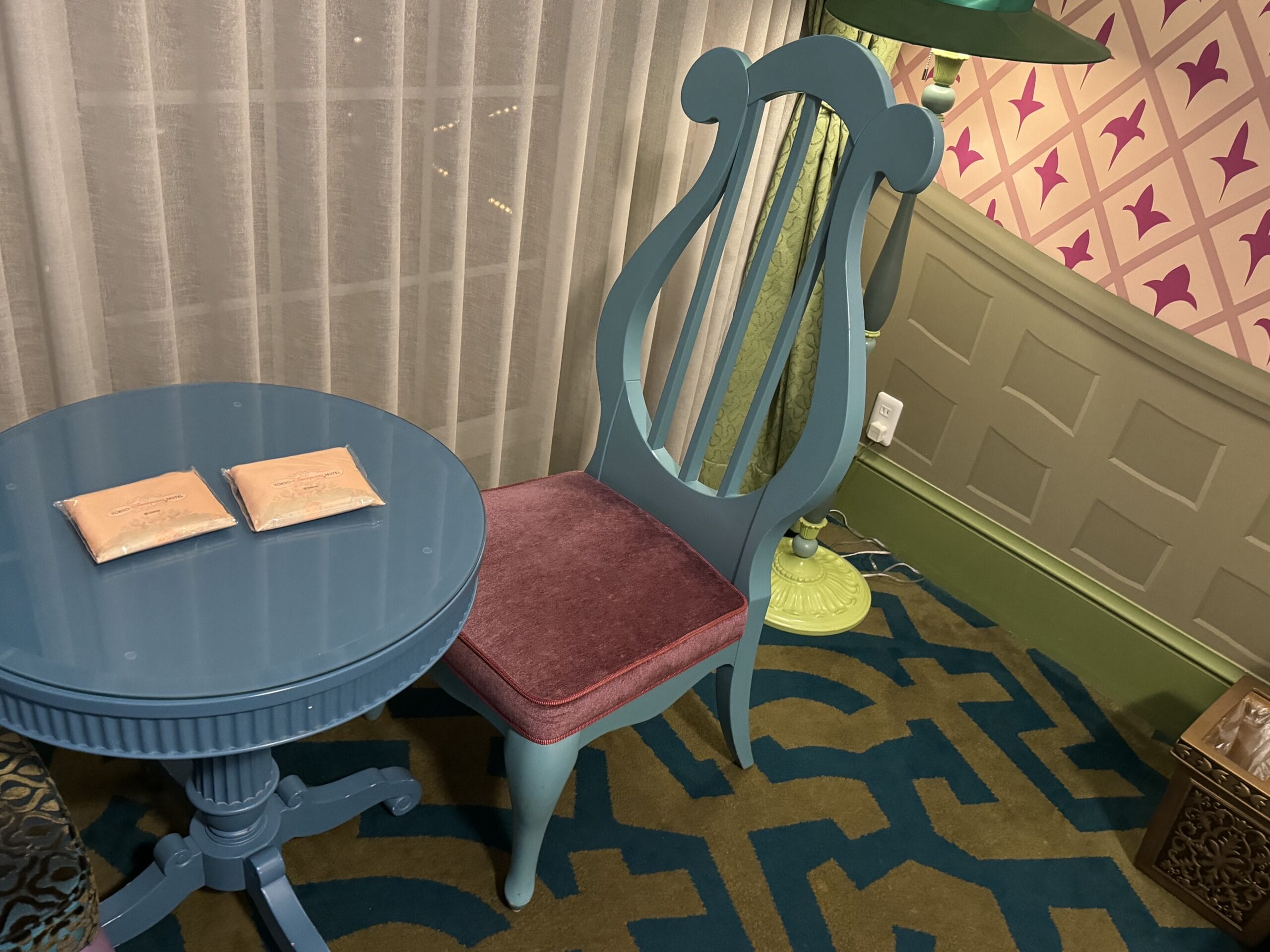 Blue round table with two wrapped items, next to a blue chair in an Alice in Wonderland hotel room tour at Tokyo Disneyland Hotel.