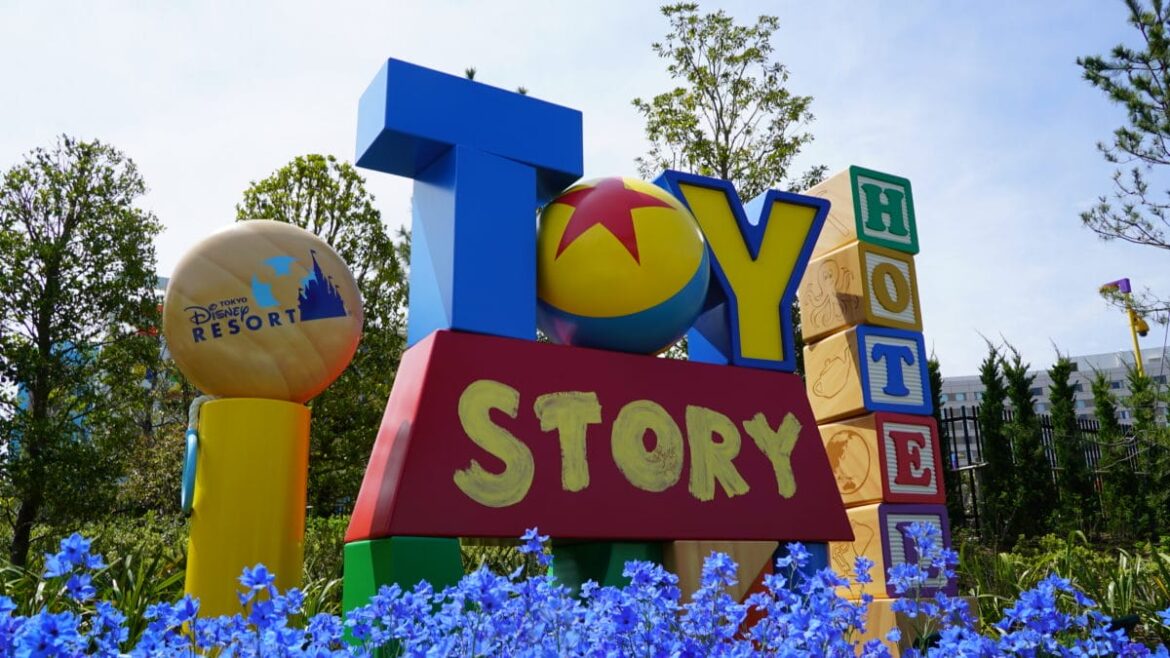 Exclusive Tokyo DisneySea Fantasy Springs Entrance Now Accessible to Guests at Toy Story Hotel Colorful "Toy Story Hotel" sign near the Fantasy Springs entrance, with playful letters, flowers, and lush greenery.