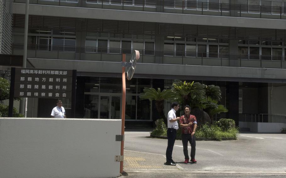 Media members stand outside Naha District Court on Okinawa.