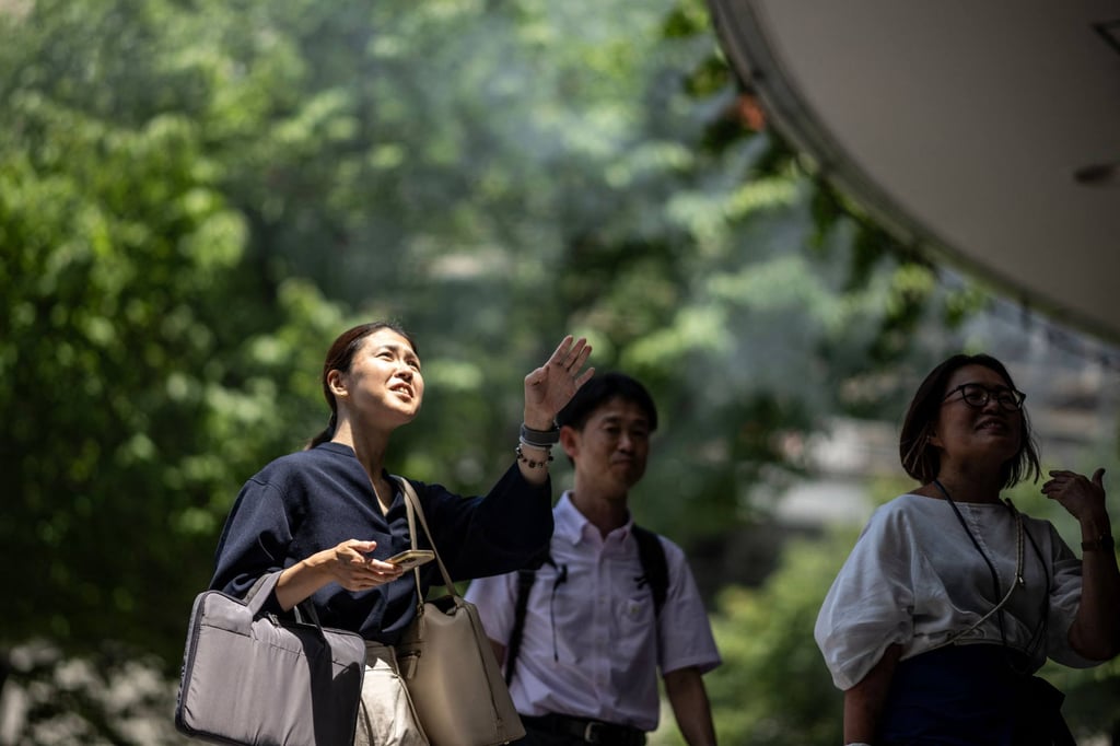 People walk down a street in the Yurakucho district in Tokyo, where temperatures topped 34 degrees Celsius on Wednesday. Photo: AFP