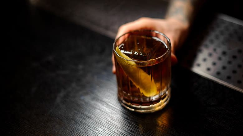 A bartender serves a whisky cocktail