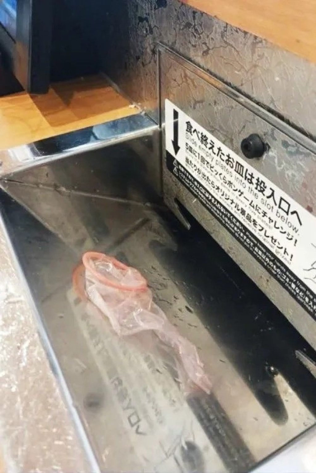 This image, showing the unwrapped condom in the slot used to collect empty plates at a sushi restaurant, went viral after being posted to social media on March 28. Photo: X