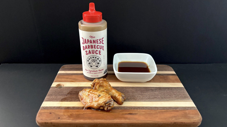 Bachan's Miso Japanese Barbecue Sauce on wooden cutting board with wings and ramekin