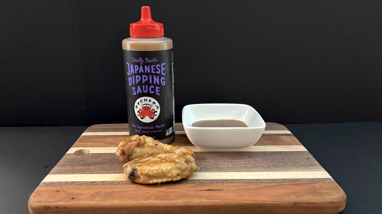 Bachan's Totally Garlic Japanese Dipping Sauce on wooden cutting board with wings and ramekin