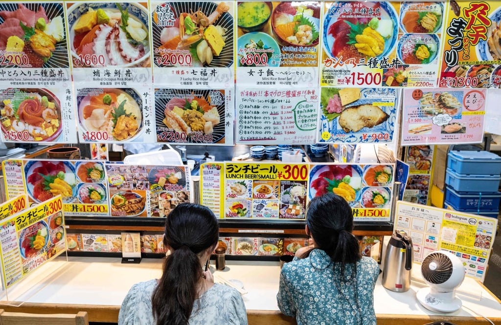Two women wait for an early morning meal at one of the many small seafood restaurants at the Tsukiji fish market. Photo: AFP