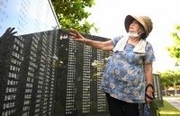 Kiyoko Arakaki, 75, gazes at the Cornerstone of Peace monument, on which the names of her relatives including her grandfather are inscribed, at Peace Memorial Park in Itoman, Okinawa Prefecture, on Okinawa Memorial Day, June 23, 2025. She commented, 