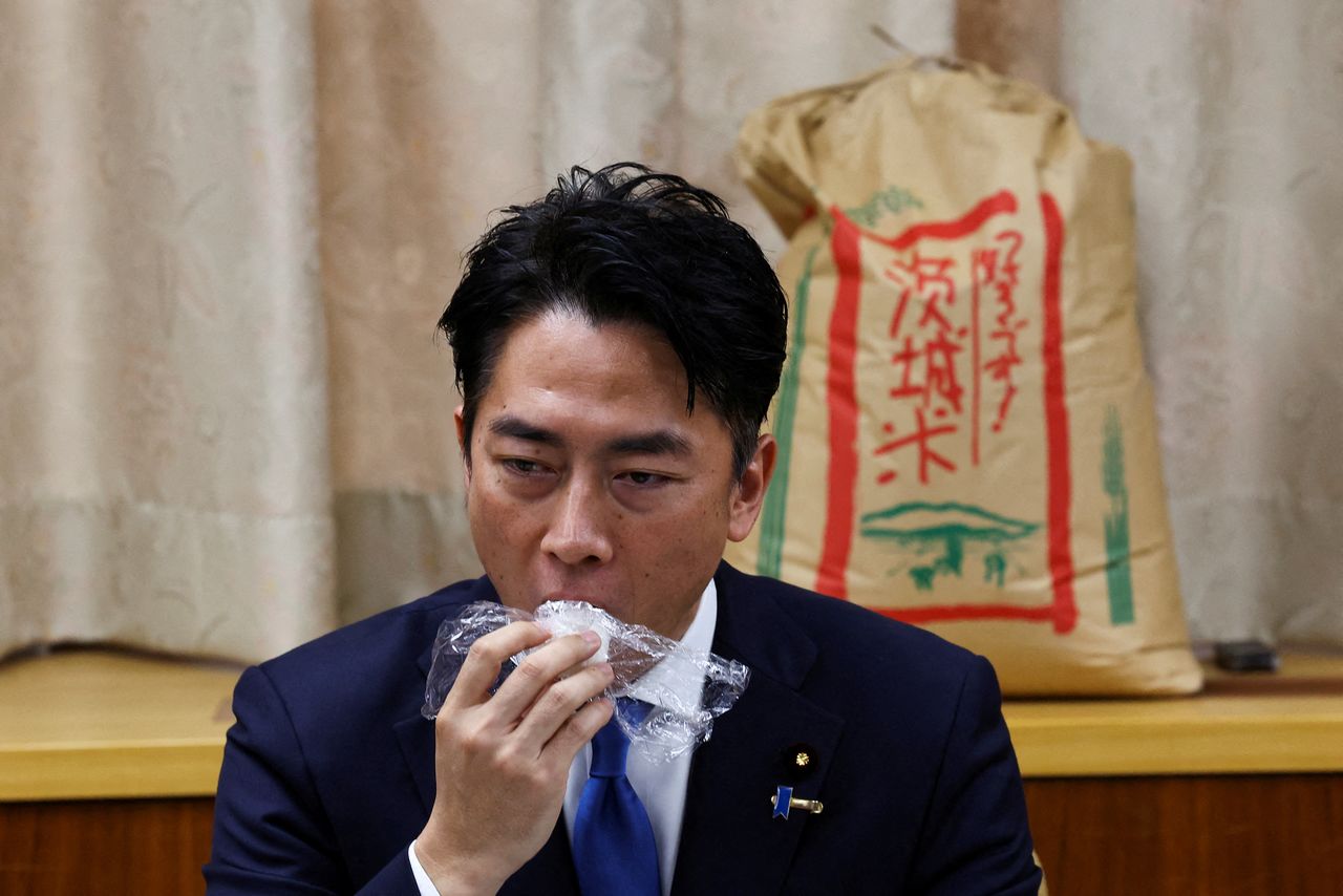 Minister of Agriculture, Forestry, and Fisheries Koizumi Shinjirō eating an onigiri as part of a blind taste test on May 29, 2025. (© Reuters)