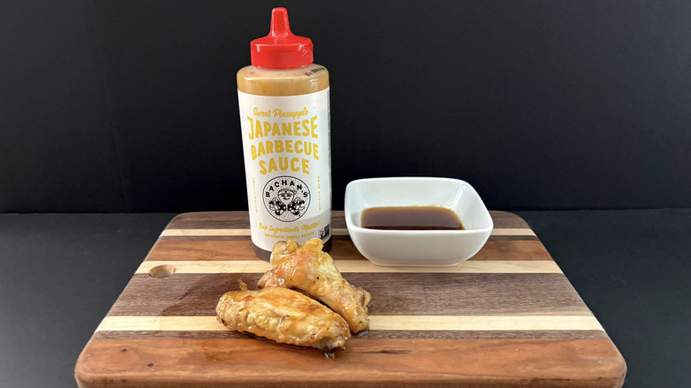 Bachan's Sweet Pineapple Japanese Barbecue Sauce on wooden cutting board with wings and ramekin