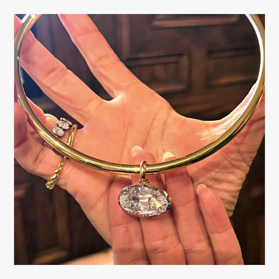Choker necklace with a large oval gemstone pendant held in a hand.