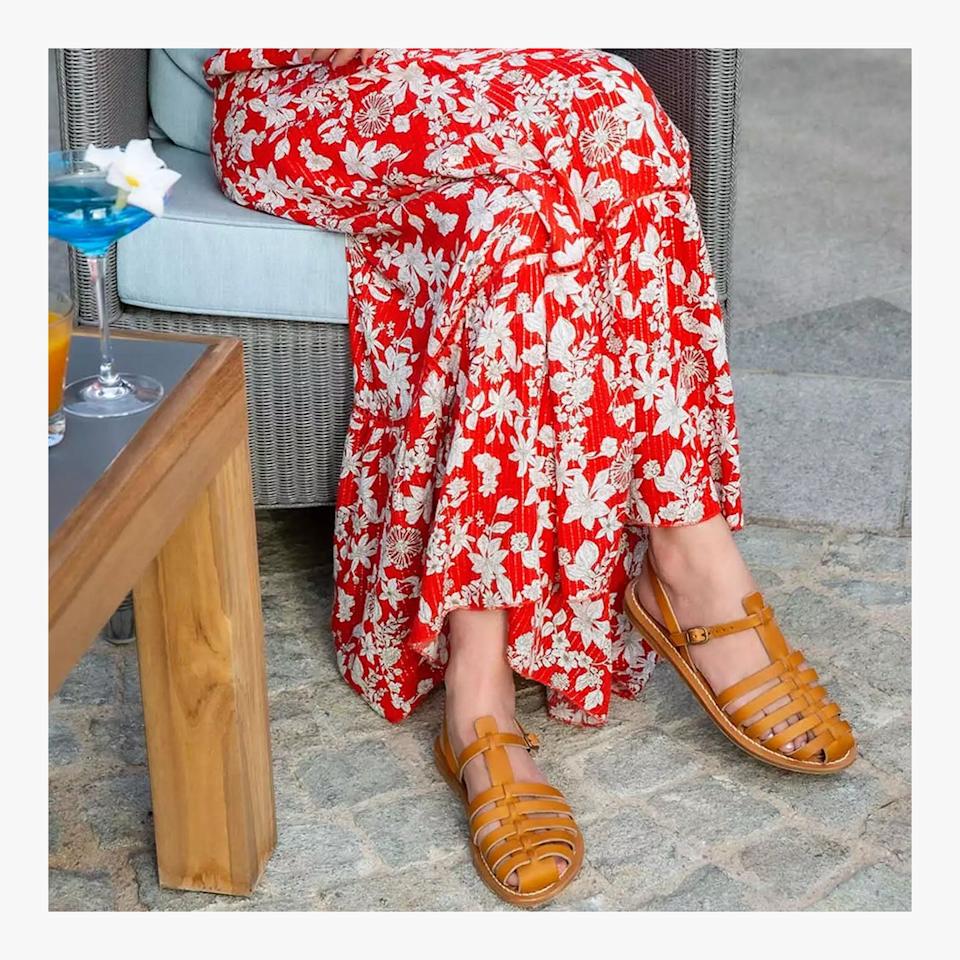 Pair of stylish yellow sandals worn with a red floral dress.