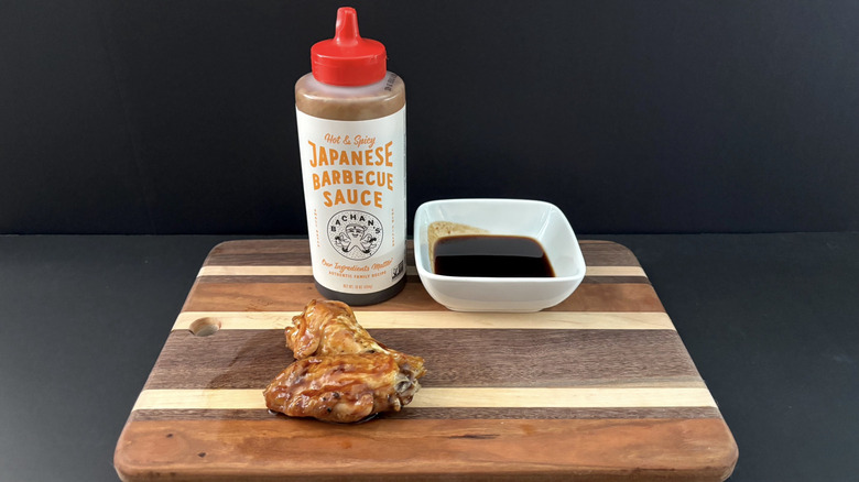 Bachan's Hot & Spicy Japanese Barbecue Sauce on wooden cutting board with wings and ramekin
