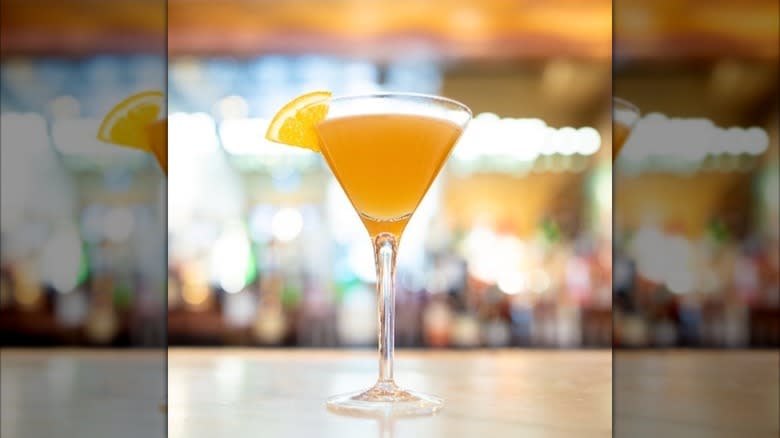 Tokyo sidecar in a coupe glass on a bar, with a lemon wedge garnish