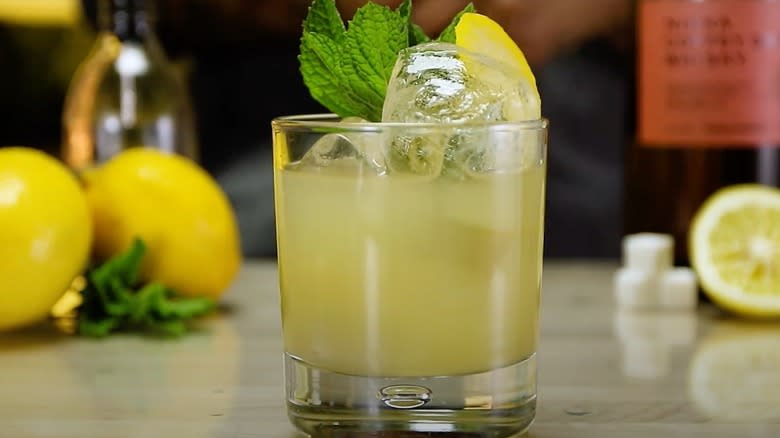 Japanese Whisky Smash in a glass with ice, garnished with a lemon slice and a sprig of mint