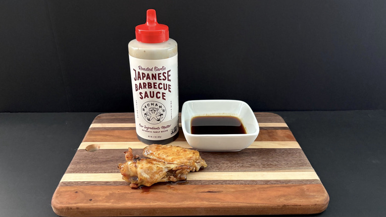 Bachan's Roasted Garlic Japanese Barbecue Sauce on wooden cutting board with wings and ramekin