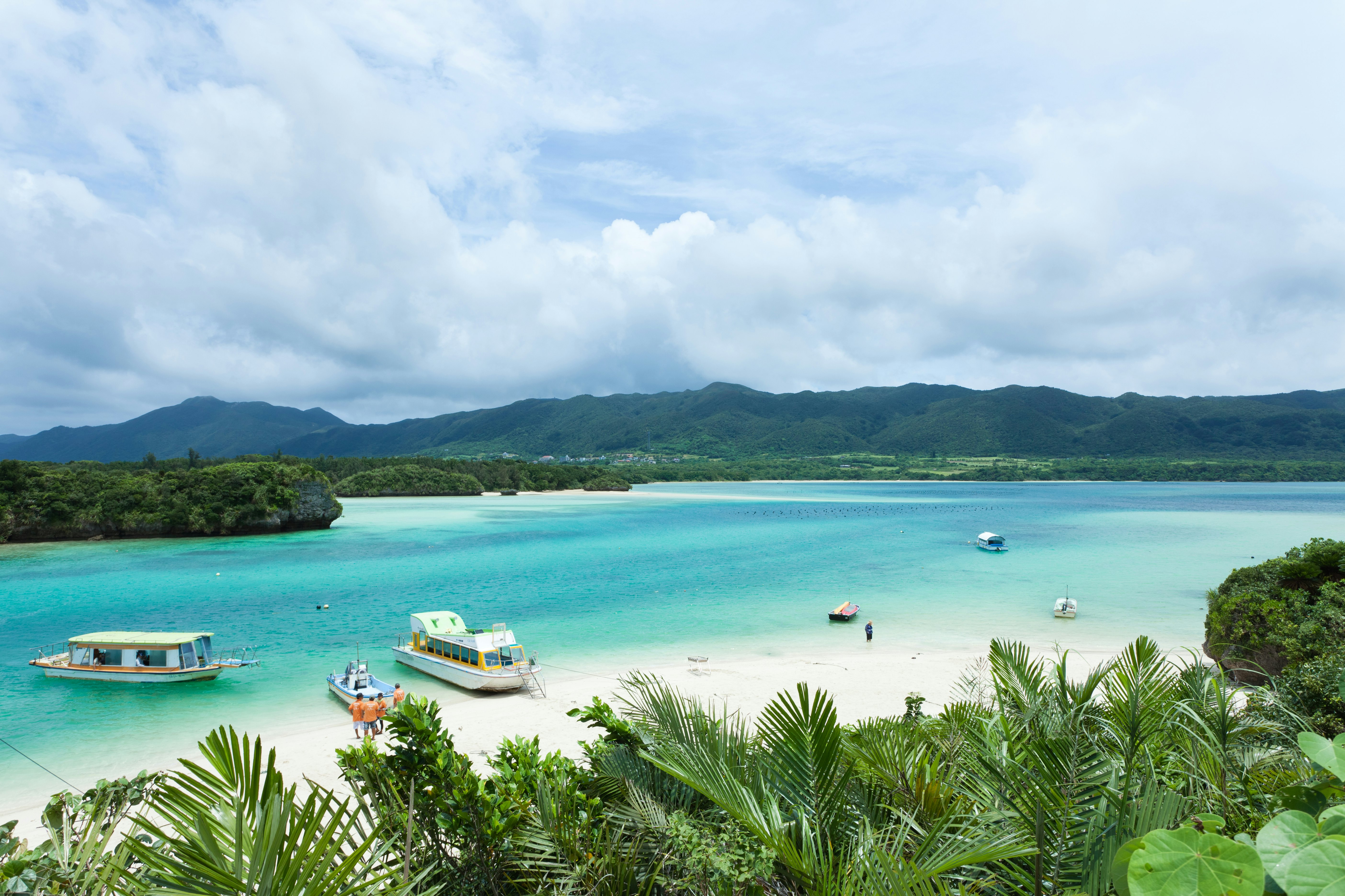An aerial view of light blue ocean and powdered white sand.