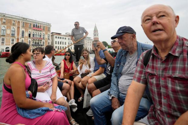 FILE - Tourists sit in a gondola during a short crossing of a canal, in Venice, Italy, Wednesday, Sept. 13, 2023. (AP Photo/Luca Bruno, File)