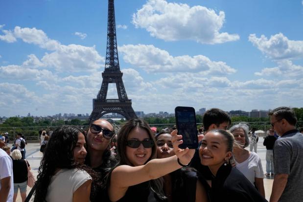 FILE - Tourists pose for a selfie with the Eiffel Tower in background, Thursday, July 6, 2023 in Paris. (AP Photo/Michel Euler, File)